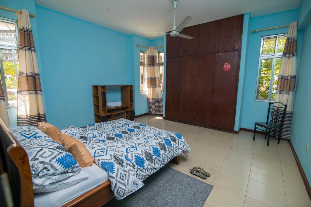 1 dormitorio con 1 cama con pared azul en 3 bedroom Apartment en Dar es Salaam