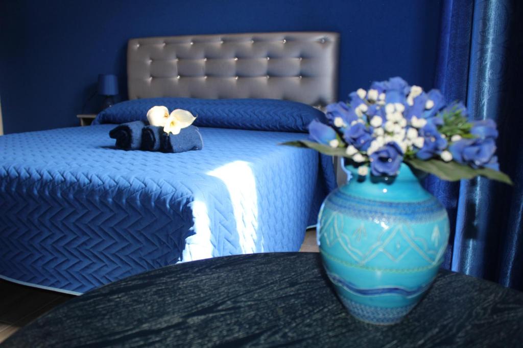 ein blaues Schlafzimmer mit einem Bett mit einer Blumenvase in der Unterkunft B&B Fontevecchia in Castelsardo