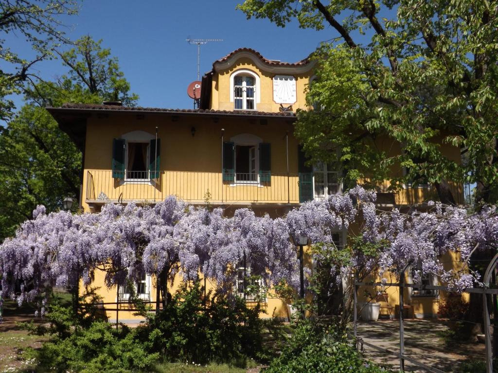 una casa con glicinas púrpuras delante de ella en Villa Mirano Bed & Breakfast, en Piossasco