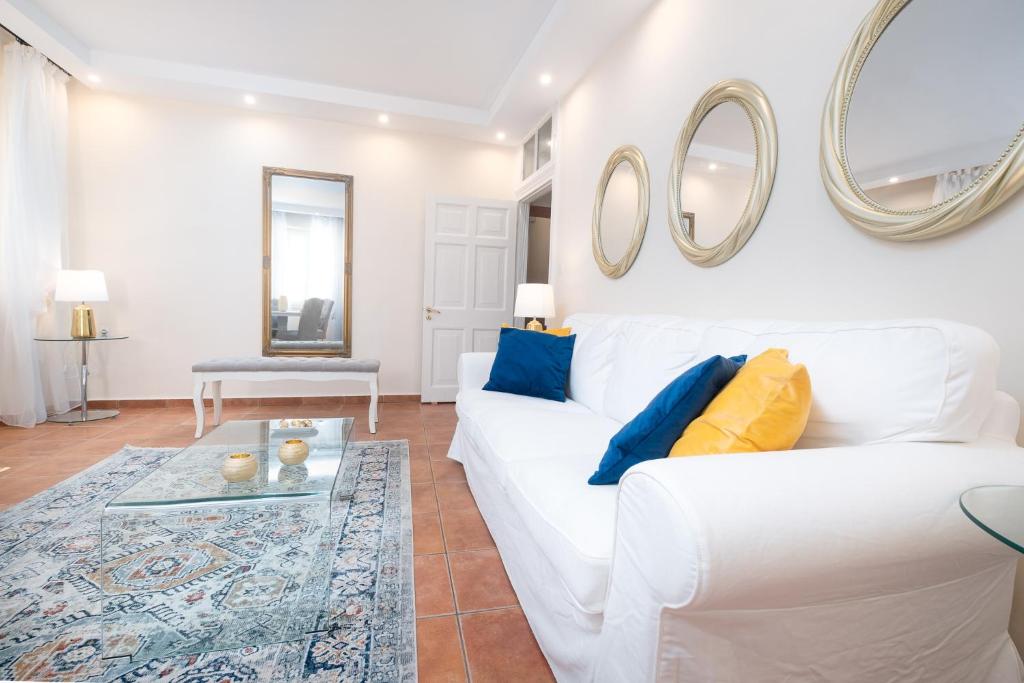 salon z białą kanapą i lustrami na ścianie w obiekcie Guilford old town Apartment w Korfu