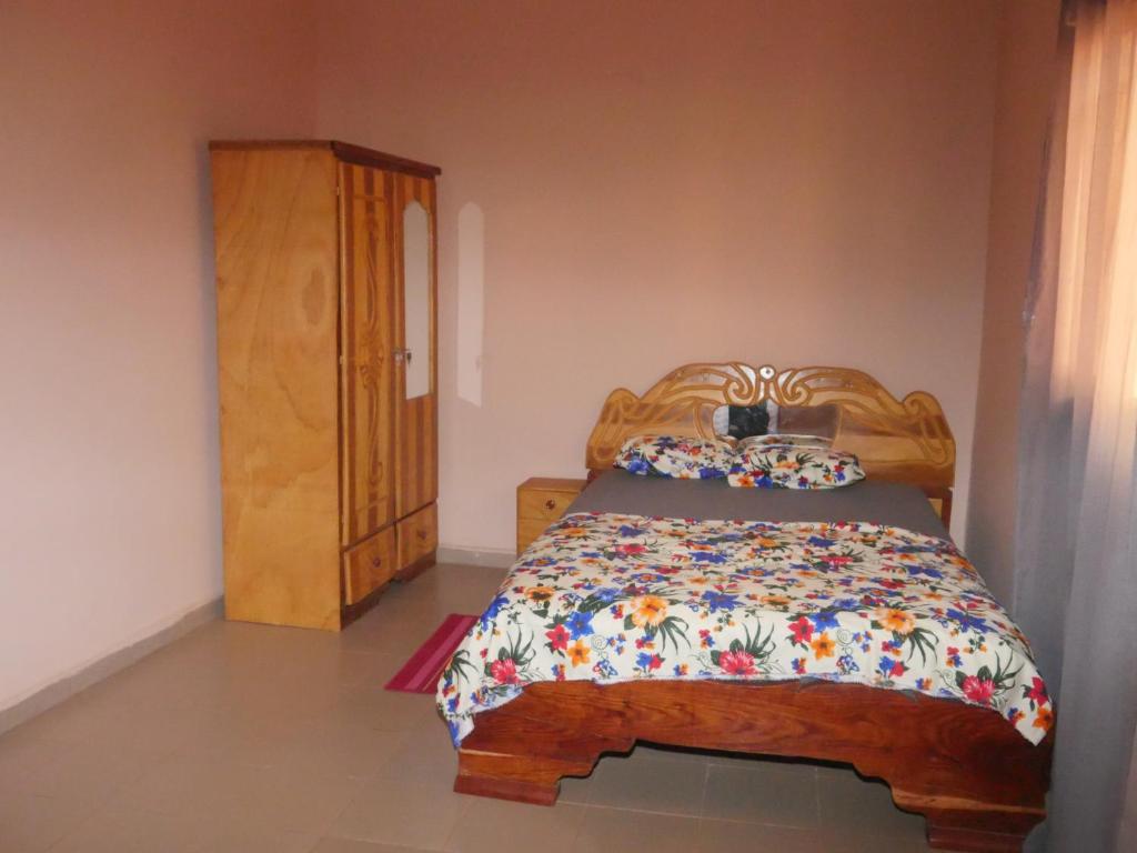 sypialnia z drewnianym łóżkiem i drewnianą szafką w obiekcie Appartement et Chambres w mieście Bamako