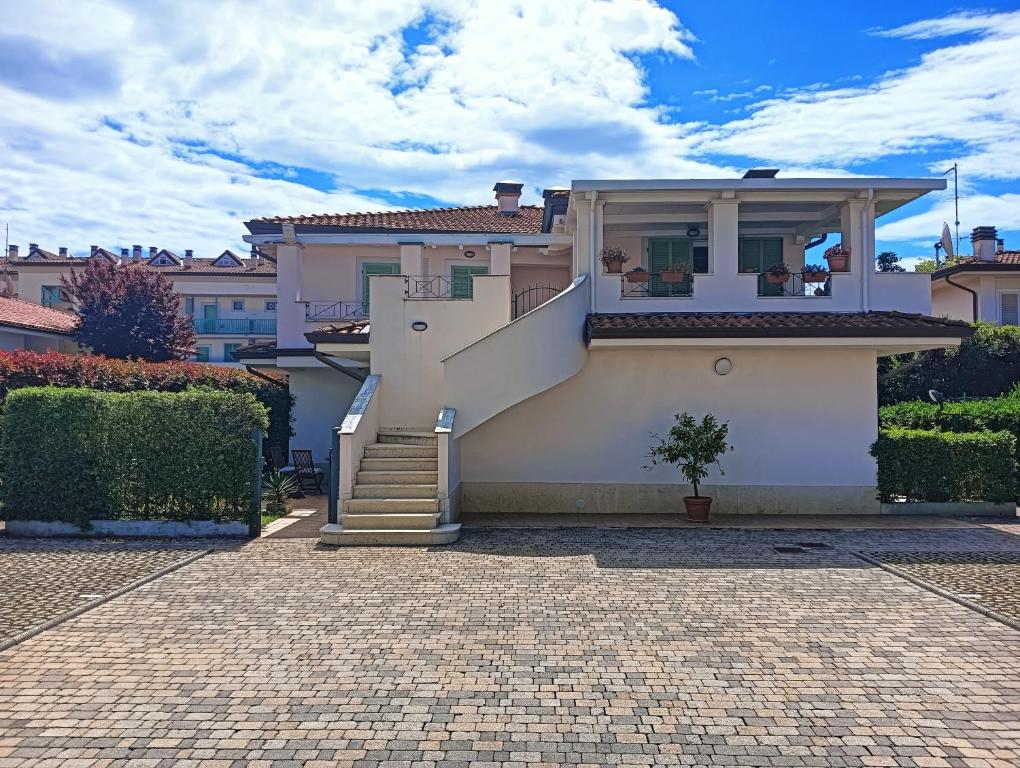 a white house with a staircase and a house at Appartamento a Forte dei Marmi con giardino e 2 posti auto in Querceta