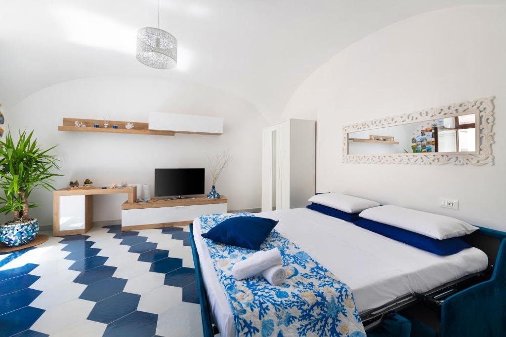 a blue and white bedroom with a bed and a tv at Appartamento luminoso e romantico ANyMA in Massa Lubrense
