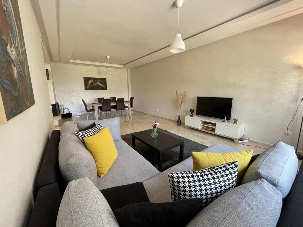un soggiorno con divano grigio e cuscini gialli di Chic & cosy Flat Near Airport lockbox fast wifi a Nouaceur