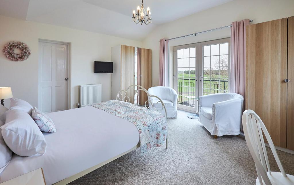 a bedroom with a bed and chairs and a balcony at Host & Stay - The Paddock in Bedlington