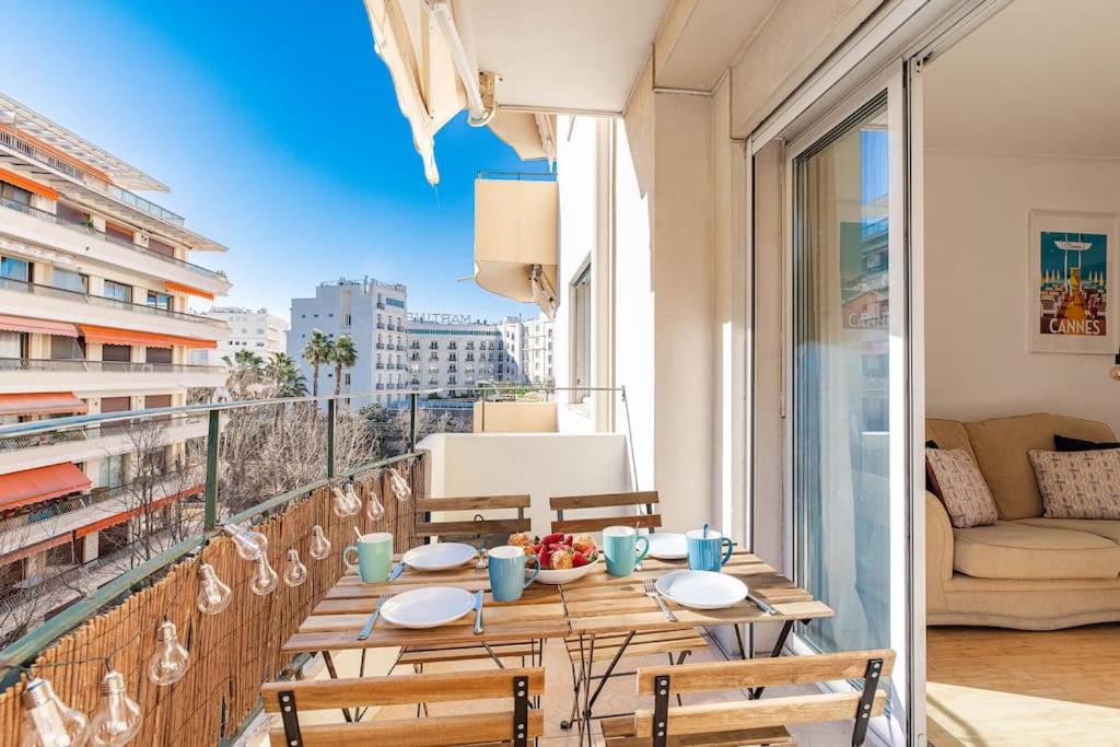 Hotel Charmant Appartement à 300 mètres des plages de la Croisette, a table on a balcony with a view of a city at Charmant Appartement à 300 mètres des plages de la Croisette in Cannes