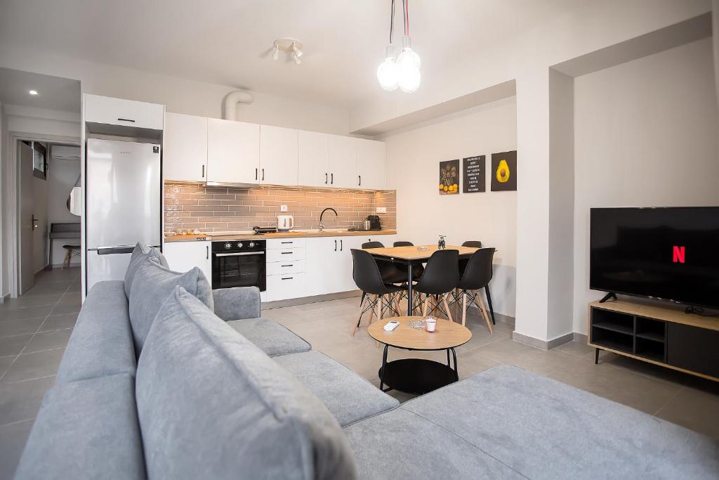 ein Wohnzimmer mit einem Sofa und einem Tisch sowie eine Küche in der Unterkunft Serenity Suites Corfu in Potamós