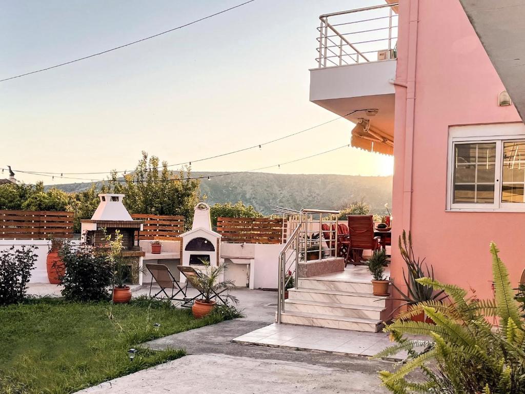 una casa de color rosa con patio trasero en Villa Anastasia en Apolakkiá