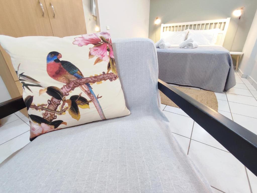 una silla con almohada de pájaro junto a una cama en Palmeira Studio, en Preveza