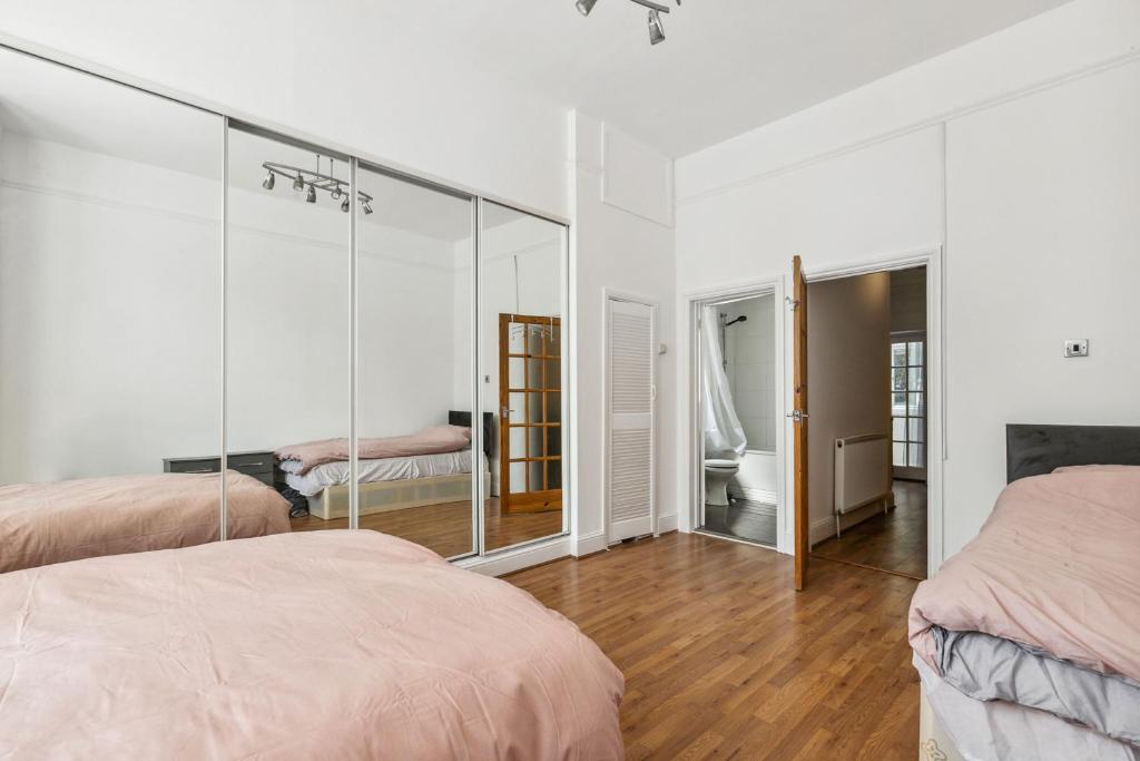 um quarto com 2 camas e um espelho em Cozy Wimbledon Apartment em Londres