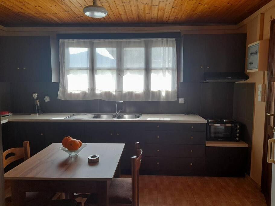 a kitchen with a table and a sink and a window at Το σπιτάκι στη Μουρνέ in Dharivianá