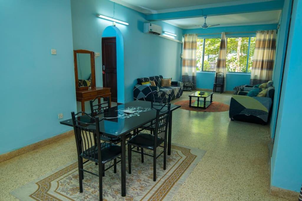 a blue room with a table and a living room at Kaanasisi 3 Bedrooms Apartment in Dar es Salaam