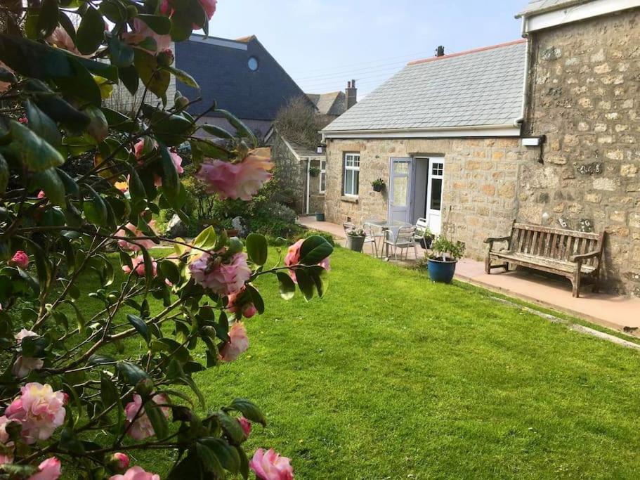 a garden with a bench in front of a house at Spacious flat St Ives former farmhouse, parking in St Ives