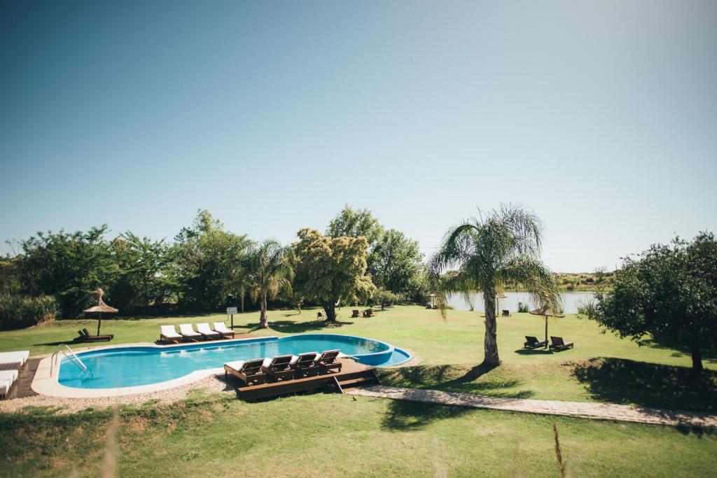a swimming pool in a field with chairs and trees at Posada Las Aguas in Gualeguaychú