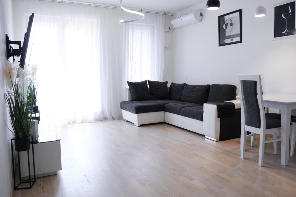 een woonkamer met een zwart-witte bank en een tafel bij D&A Apartments Obozowa in Warschau