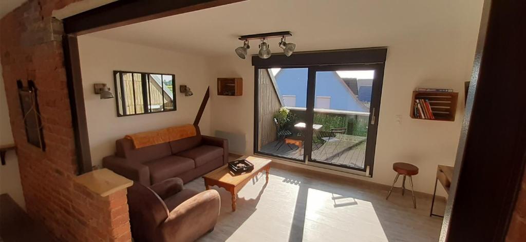 een woonkamer met een bank en een groot raam bij Le grenier de Véro in Houssen