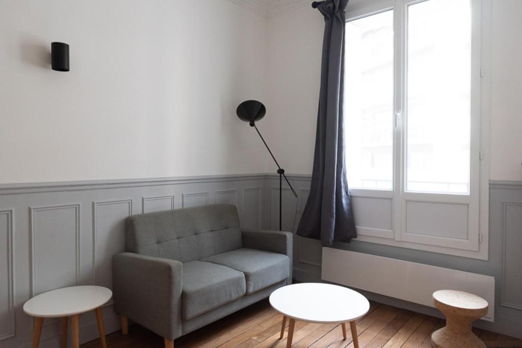 ein Wohnzimmer mit einem Sofa und 2 Tischen in der Unterkunft Charming love nest near Montmartre in Paris