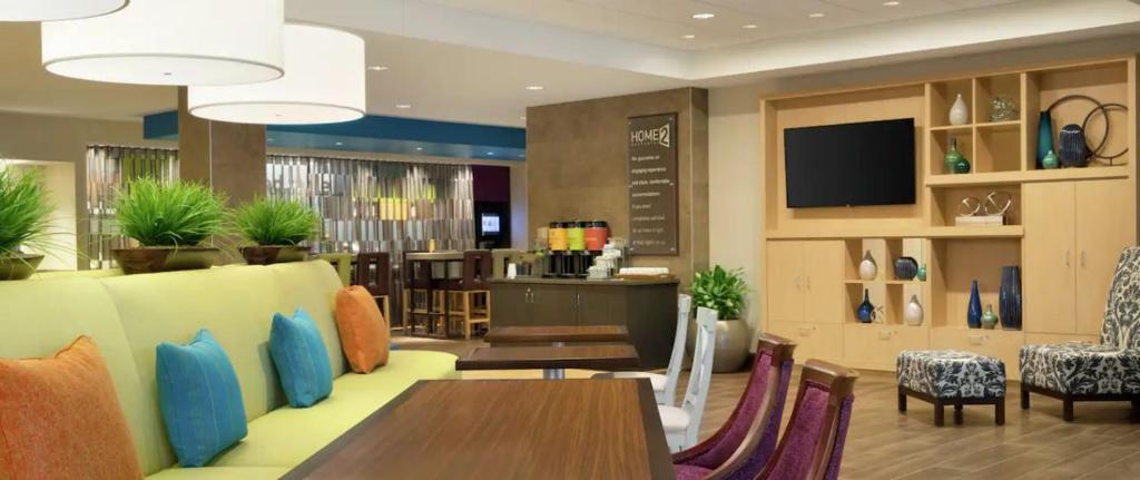 a restaurant with tables and chairs and a television at Home2 Suites By Hilton Sacramento At Csus in Sacramento