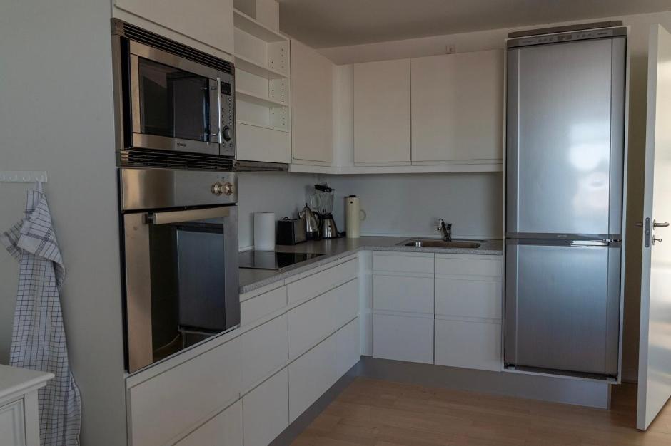 a kitchen with white cabinets and a stainless steel refrigerator at Hotel Nuka in Ilulissat