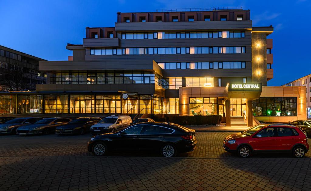 un parking avec des voitures garées devant un bâtiment dans l'établissement HOTEL CENTRAL, à Paşcani