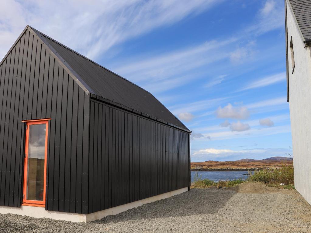 een zwart huis met een rood raam bij North Light Studio in Carinish