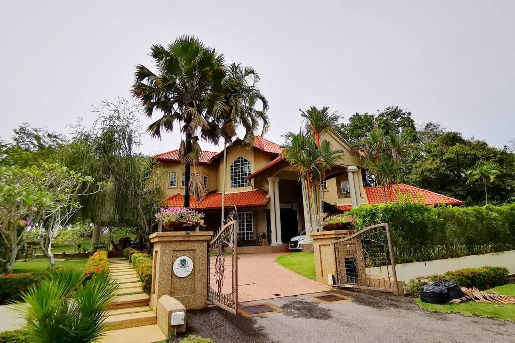 een huis met een palmboom ervoor bij Tiara Golf Villa With Pool in Melaka