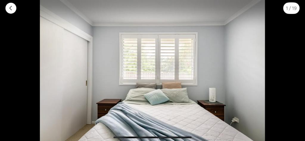 a white bedroom with a bed and a window at Guest ensuite 7 minutes from airport in Melbourne