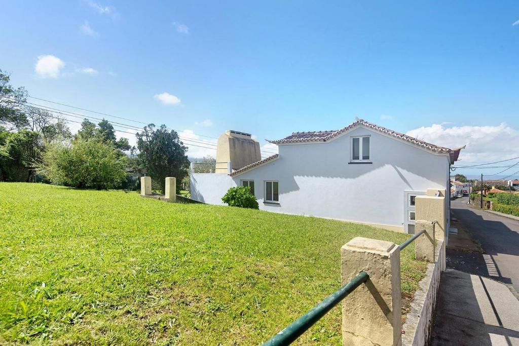 Biały dom z zielonym trawnikiem przed nim w obiekcie Casa da Batalha w mieście Ponta Delgada
