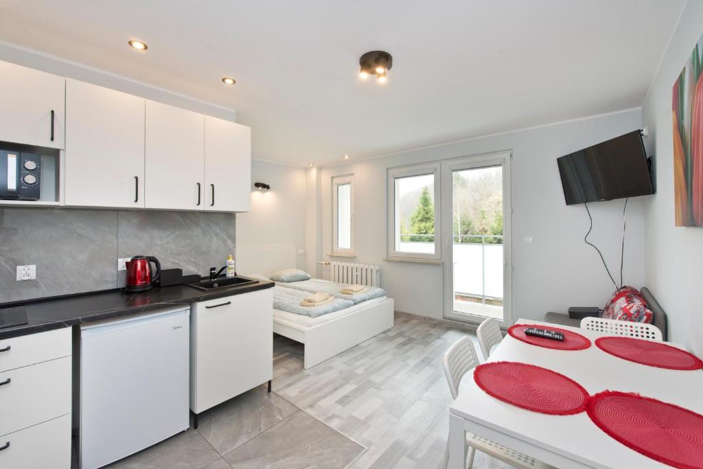 a kitchen with white cabinets and a table with red plates at YOURAPART NORWIDA in Gdynia