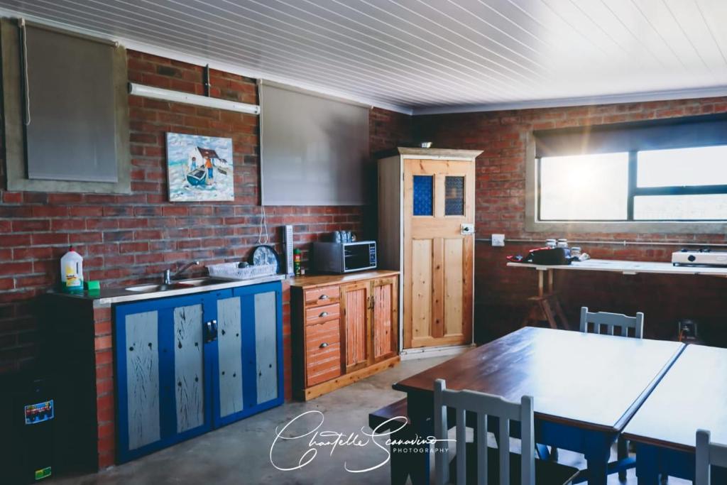 a kitchen with a table and a brick wall at Oppi Plaas See Uitsig in Groot Brak Rivier