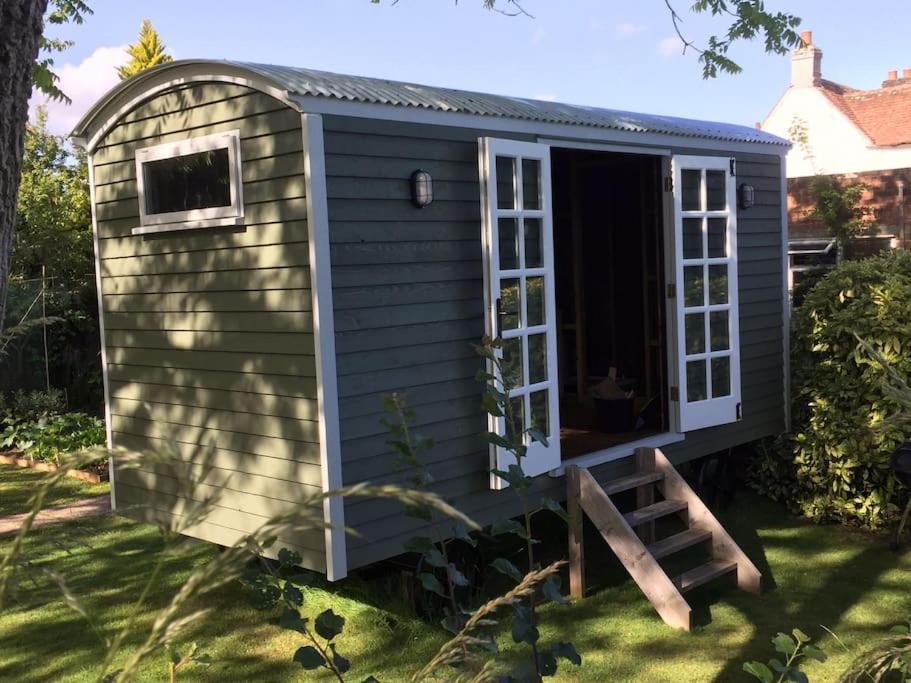 a shed with a door and a window at The Nutbourne Hut - shepherd's hut - pint-sized luxury in Hambrook
