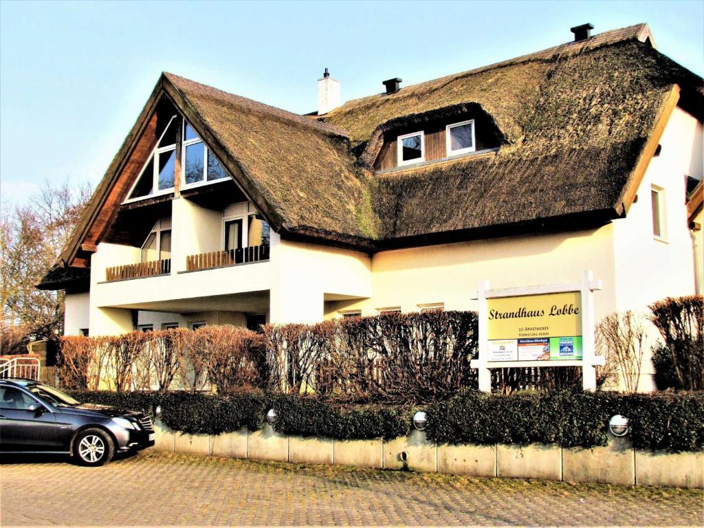 a house with a roof with a car parked in front at Strandhaus Lobbe 45481 in Lobbe