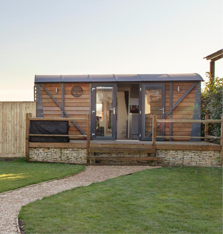 a modular home with a fence and grass at Holly Lodge - Quirky Shepherd's Hut With Hot Tub - Bespoke Made From A Salvaged Railway Carriage in Boston