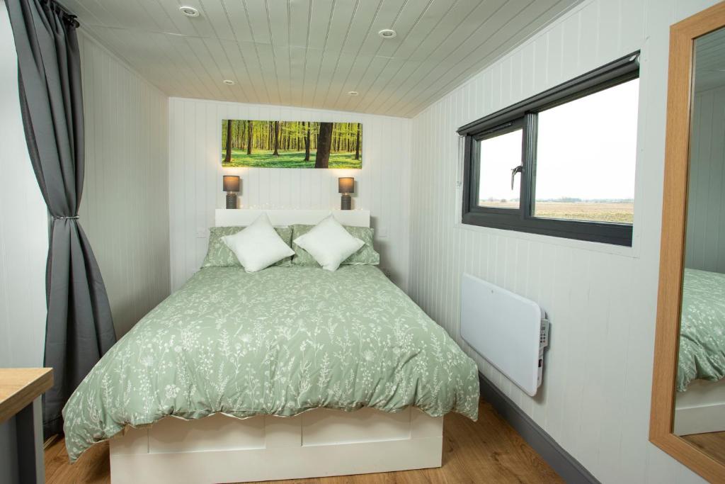 a bedroom with a bed and a window at Holly Lodge - Quirky Shepherd's Hut With Hot Tub - Bespoke Made From A Salvaged Railway Carriage in Boston