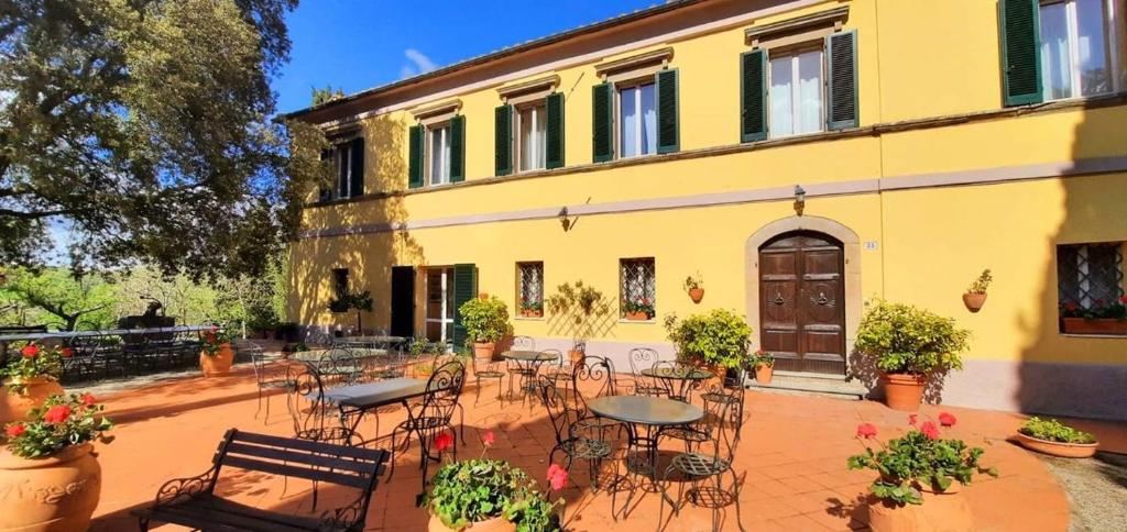 a courtyard with tables and chairs in front of a yellow building at Fattoria La Palazzina in Radicofani