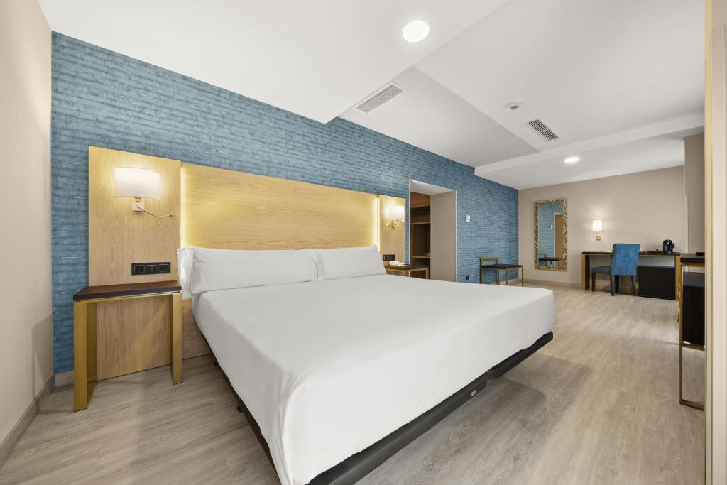 - une chambre avec un grand lit blanc et un mur bleu dans l'établissement Hotel Zentral Ramiro I Oviedo, à Oviedo