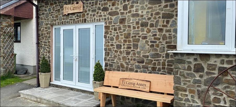 a wooden bench sitting outside of a stone building at Ty Cerrig seaside Annexe, New Quay in New Quay