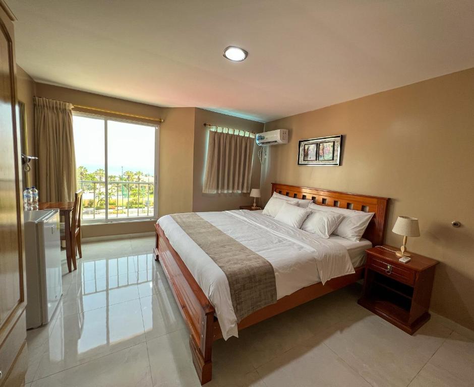 een slaapkamer met een bed en een groot raam bij Apart Hotel Hamilton in Manta