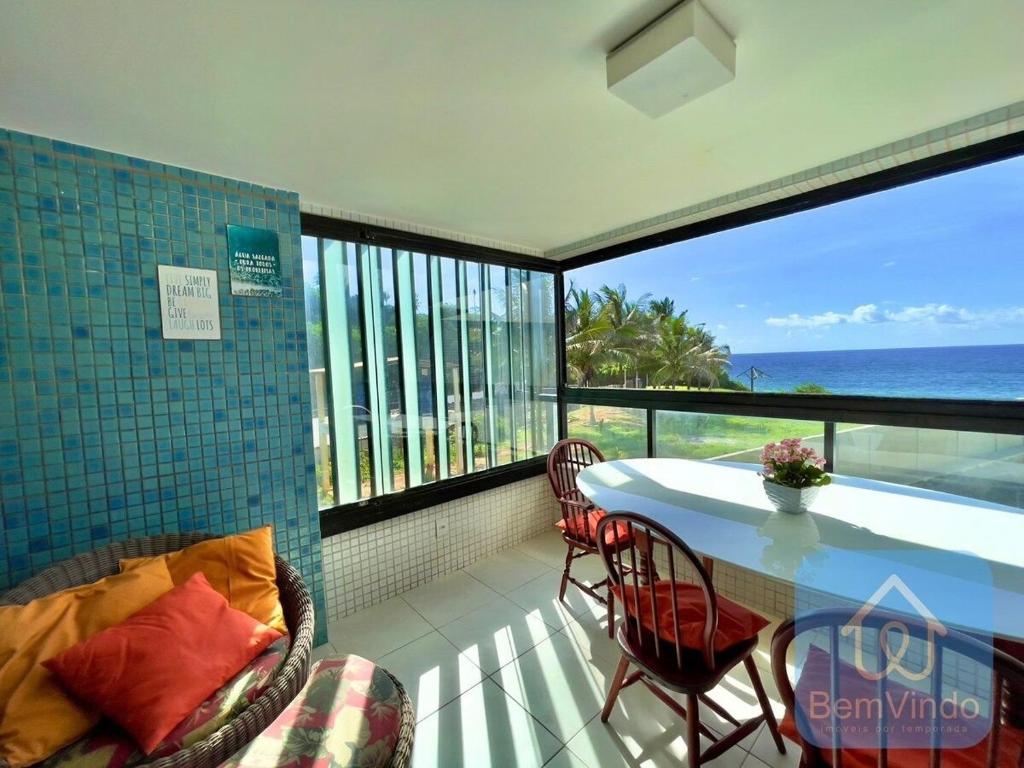 balcón con mesa, sillas y vistas al océano en Apartamento completo e pé na areia no Rio Vermelho, en Salvador