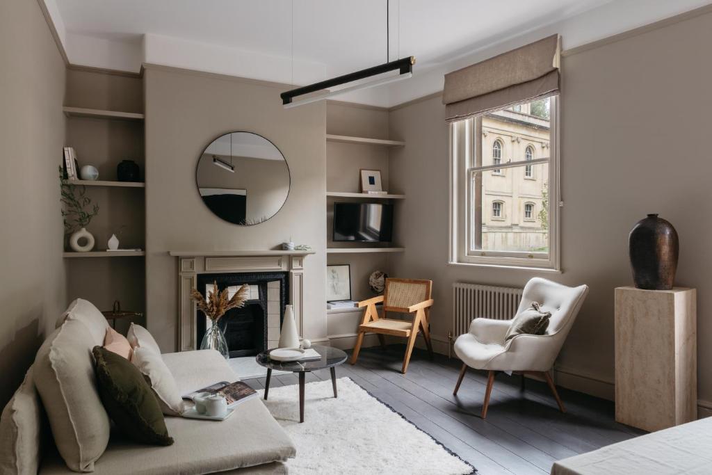 een woonkamer met een bank, stoelen en een spiegel bij The Curator's Apartment - 2 Bedrooms with parking in Bath