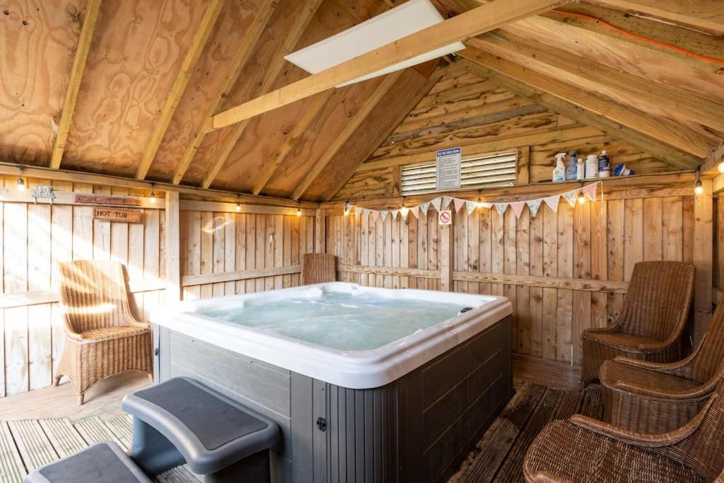 a hot tub in a wooden room with chairs at The Shed in Durham