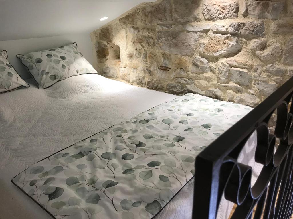 a bedroom with a bed with a stone wall at Le pigeonnier du beffroi in Bruniquel