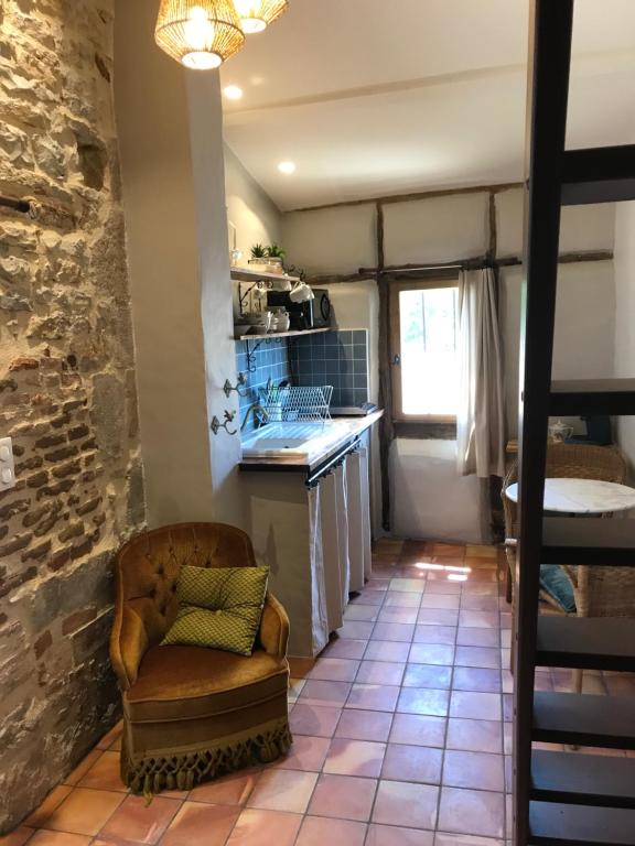 a kitchen with a table and a chair in a room at Le pigeonnier du beffroi in Bruniquel