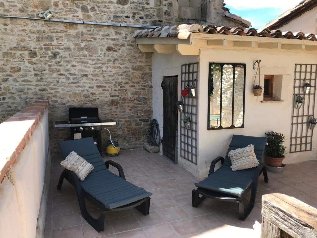 a patio with chairs and a table and a grill at Le pigeonnier du beffroi in Bruniquel