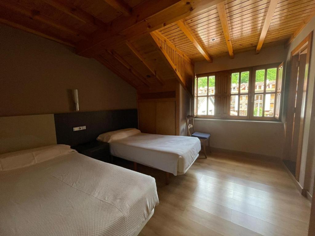 sypialnia z 2 łóżkami i dużym oknem w obiekcie PENSION CASA MIÑO w mieście Pola de Somiedo