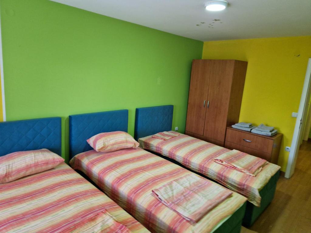 two beds in a room with green walls at Greenspace in Niš