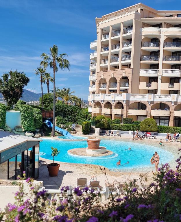 un hôtel avec une piscine devant un immeuble dans l'établissement Magnifique T2 Climatisation - Grande Terrasse, Piscine et apercu Mer, à Cannes
