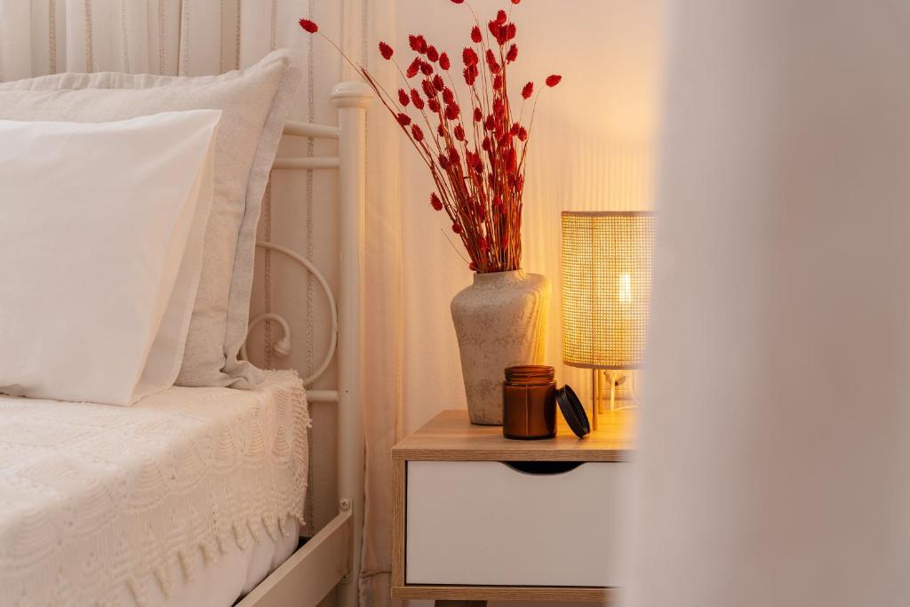 Un jarrón con flores en una mesita de noche junto a una cama en Orkos Naxian Wave 3, en Mikri Vigla