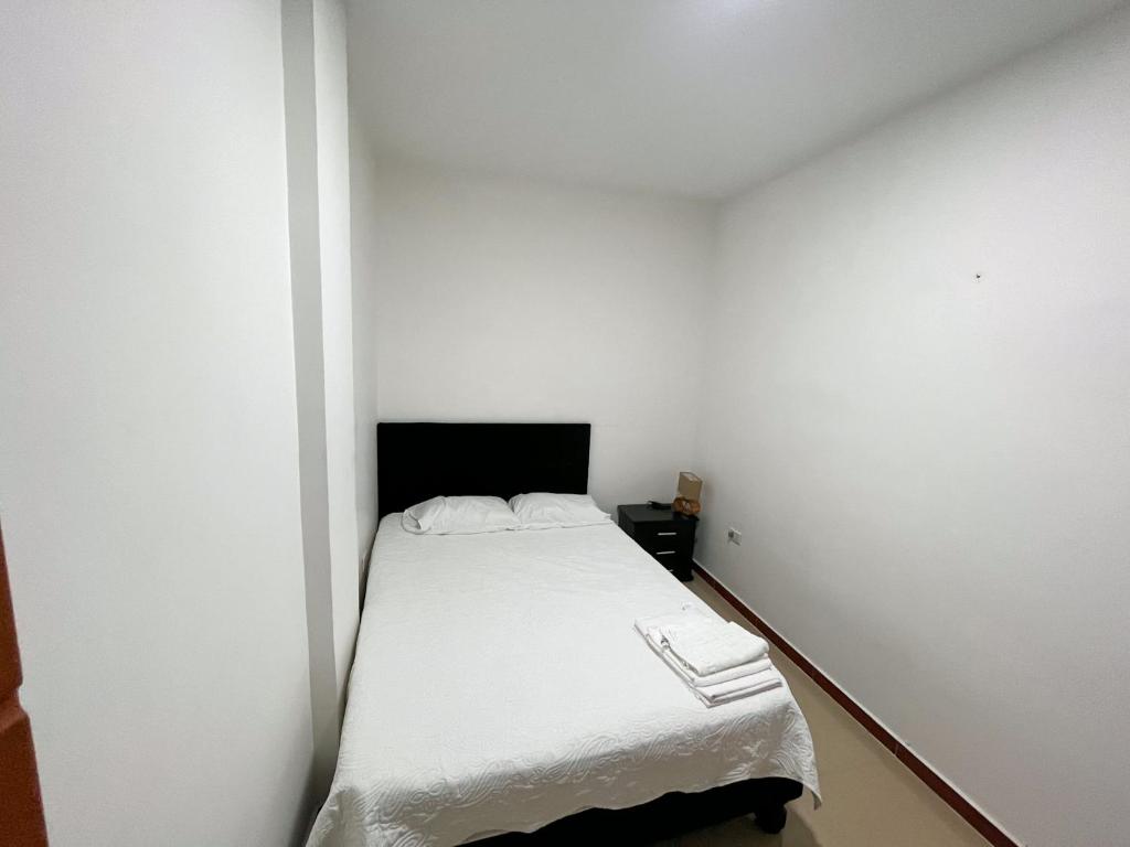 Habitación blanca pequeña con cama. en Hermoso y acogedor apartamento, en Cali