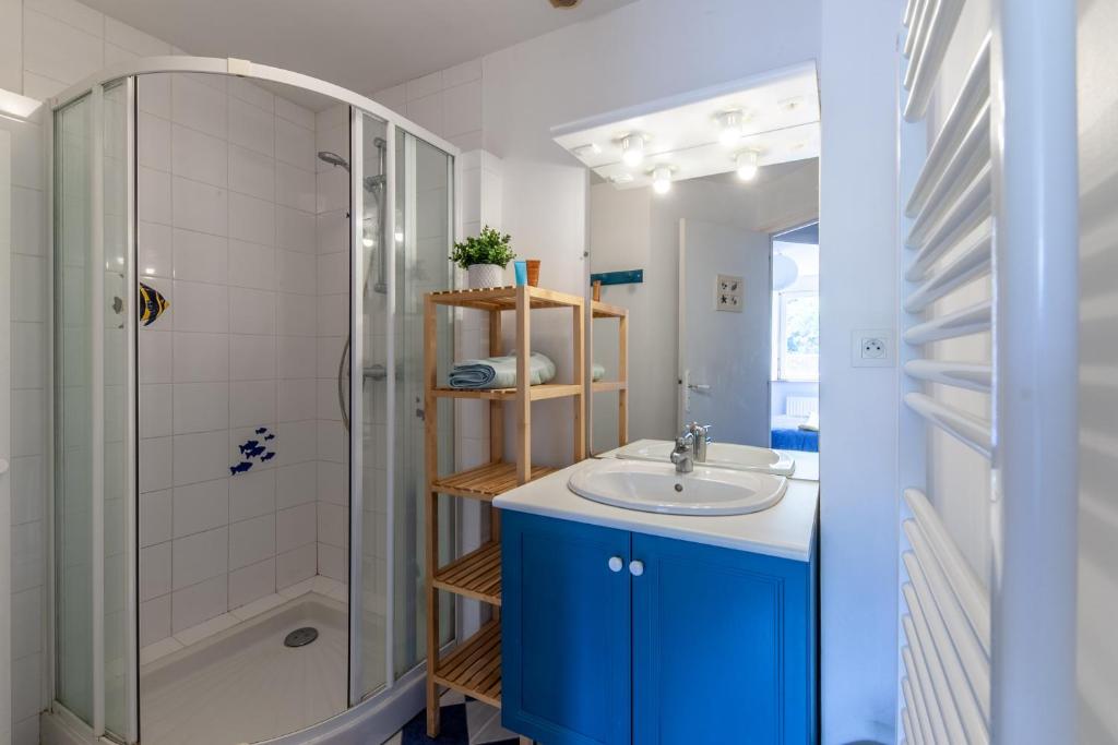 W łazience znajduje się niebieska umywalka i prysznic. w obiekcie La Grange - Charmante maison à Langrune-sur-mer w mieście Langrune-sur-Mer